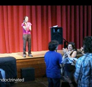 Clare onstage as Keith and Nancy look at each other and applaud