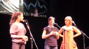 Kristin Kreuk, Nicki Clyne and Allison Mack put on a show to promote Keith Raniere. Note the banner in the background.