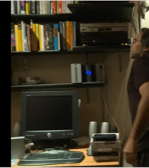 Raniere in his library. The hard drive with the blue light was right above his computer.