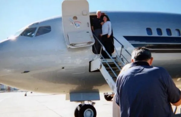 Bill Clinton and Ghislaine Maxwell pose at the door of Jeffrey Epstein's Boeing 727, called the Lolita Express.