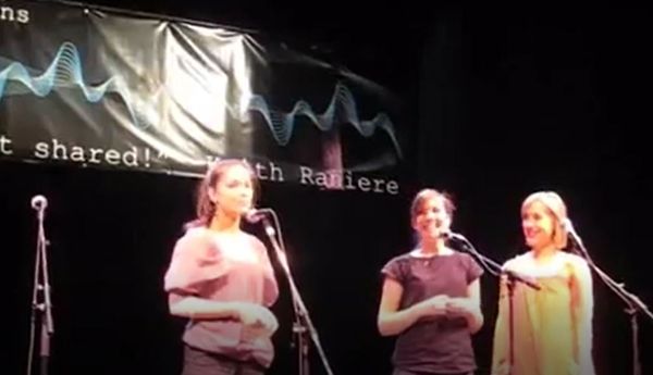 Actresses Kristin Kreuk, Nicki Clyne and Allison Mack perform as volunteers in an a-Cappella concert for Keith Raniere in Albany, Dec. 2007. Note Keith Raniere's name in the background. Raniere was accused of using the concert and the actresses as an attempt to recruit college students into NXIVM.