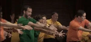 Emiliano Salinas [green t shirt] dances for his master Keith Raniere.