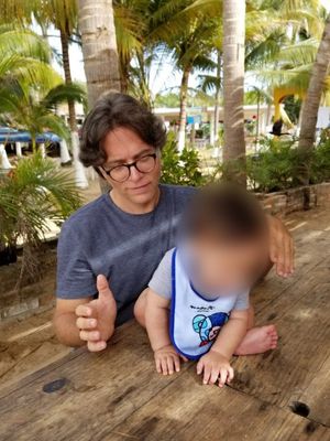 Truth Evidence D.1:2  Raniere and his son at a beach restaurant in Chacala. Note: Photo of child is blurred so as not to designate as public figure.